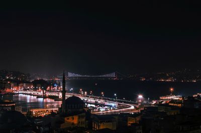 Illuminated bridge over river against sky at night