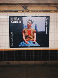 Portrait of young woman standing against wall