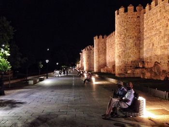 Man standing on illuminated city street at night