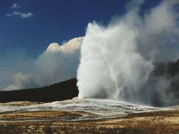 Scenic view of water spraying from geyser against sky