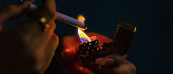 Close-up of hand holding lit cigarette lighter