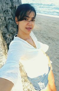 Portrait of smiling young woman sitting on beach