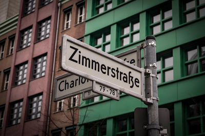 Low angle view of road sign against buildings in city