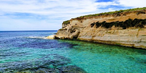 Rock formation by sea against blue sky