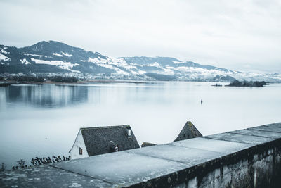 Scenic view of lake by snowcapped mountains against sky