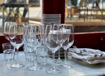 Glasses, plates and cutleries. clean wine and water glasses are on a marble table by the window