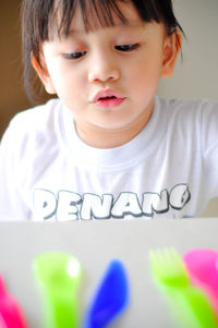 Close-up of girl playing with plastic cutlery on table