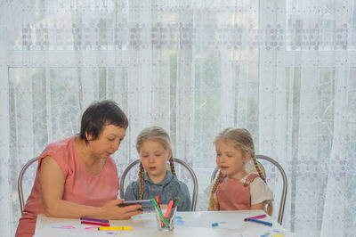 Grandmother and granddaughters looking at mobile phone at home