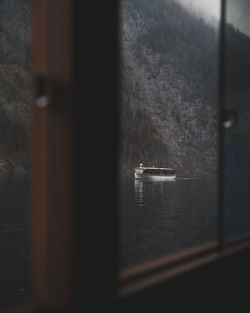 Boat sailing on sea seen through window