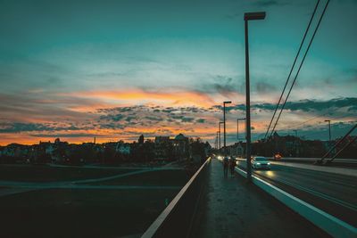 Road in city against sky at sunset