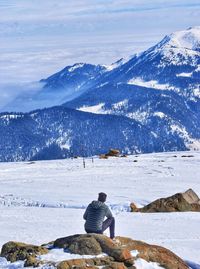 Rear view of person looking at snowcapped mountain