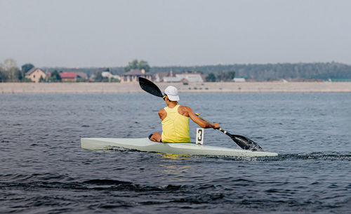 Rear view of man kayaking in lake during event