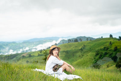 Full length of man sitting on land against sky