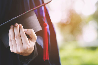 Midsection of person holding mortarboard