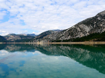 Scenic view of lake and mountains against cloudy sky