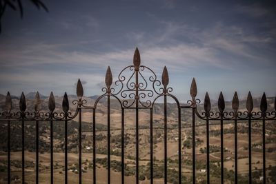 Metallic fence on land against sky