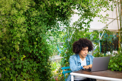 Young woman using laptop while sitting at park