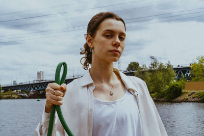 Portrait of confident young non-binary person holding garden hose