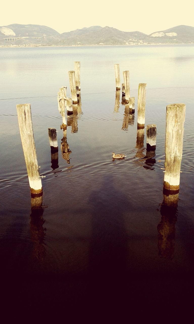 water, sea, tranquility, tranquil scene, wooden post, wood - material, lake, nature, pier, scenics, reflection, in a row, beauty in nature, day, outdoors, nautical vessel, no people, mountain, idyllic, moored