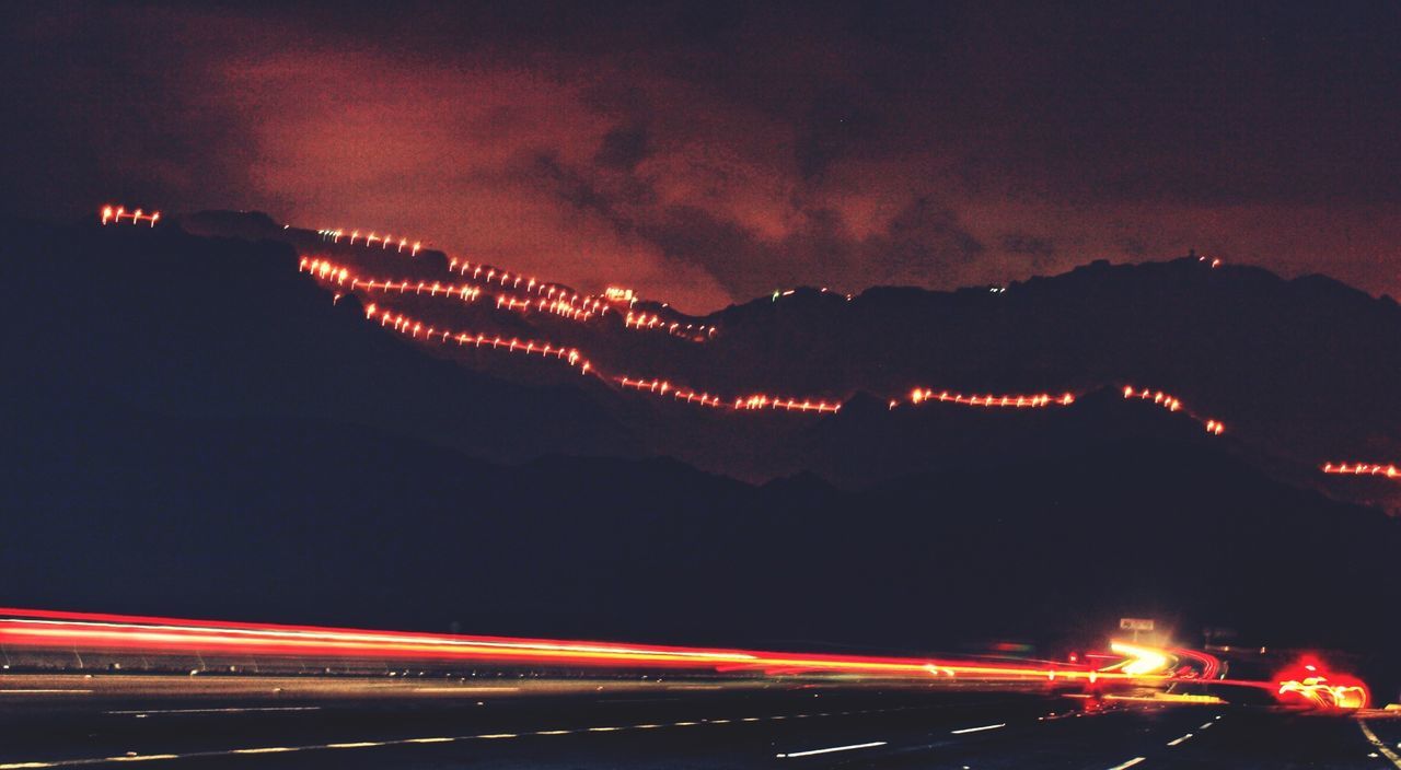 illuminated, night, long exposure, light trail, sky, motion, speed, transportation, road, blurred motion, city, red, multi colored, built structure, architecture, outdoors, mountain, high angle view, dusk, street light