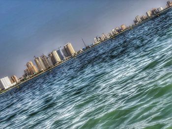 Modern buildings by sea against sky