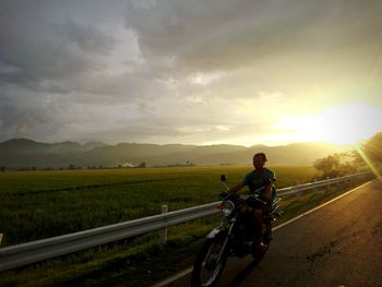 Man riding bicycle on agricultural field against sky