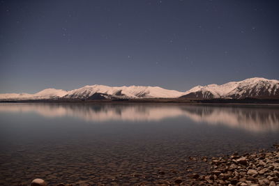 Scenic view of lake by mountains against sky at night