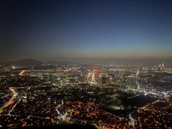 High angle view of illuminated city buildings against clear sky