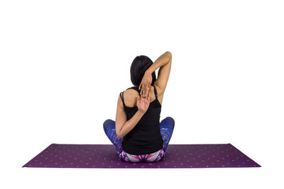 Full length of woman sitting on floor against white background