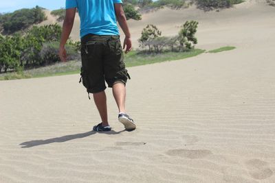 Low section of man walking on sand in desert