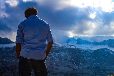 Rear view of man standing by sea against sky