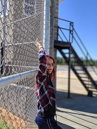 Midsection of person standing by chainlink fence