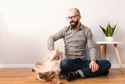 Man playing with dog while sitting on floor