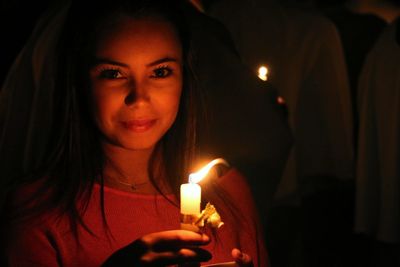 Portrait of young woman holding illuminated candle