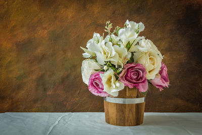 Purple roses and white roses artificial on a brown background with space for text input.