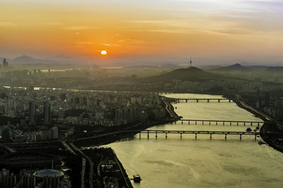 High angle view of river by buildings against sky during sunset