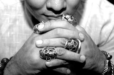 Close-up of man with hands clasped wearing rings