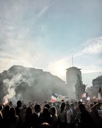 People protesting in city against cloudy sky