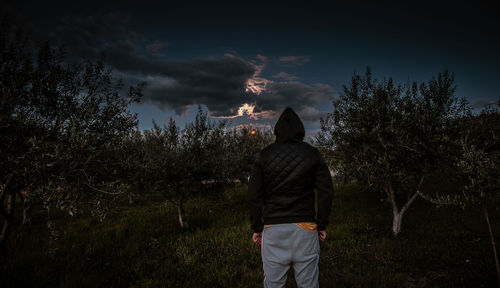 Rear view of man standing on field against sky