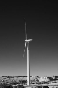 Windmills on sea against clear sky