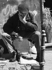 Thoughtful man sitting on chair at sidewalk