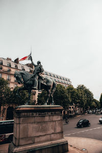 Statue in city against clear sky