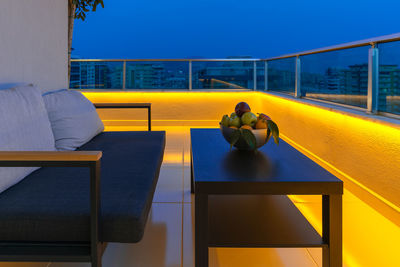 View of a cozy outdoor terrace with an armchair, a coffee table and a fruit bowl, led lighting 