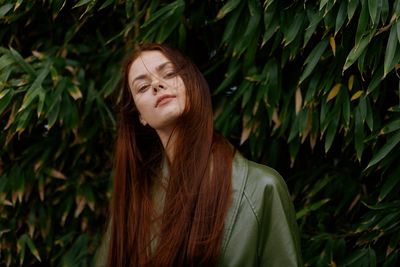 Portrait of young woman standing against plants