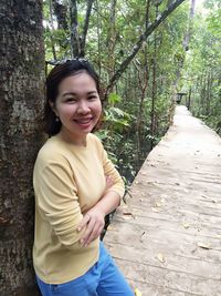 Portrait of smiling young woman standing against trees