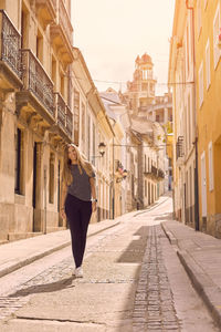 Woman on street amidst buildings in city