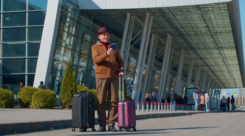 Man standing with luggage outside airport