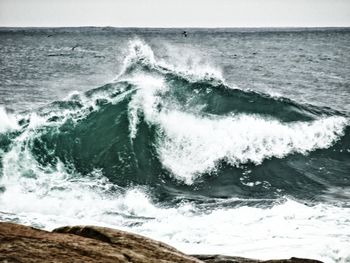 Waves splashing on sea against sky