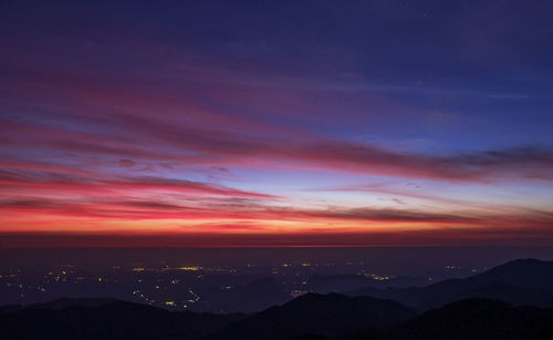 Scenic view of dramatic sky over silhouette landscape during sunset