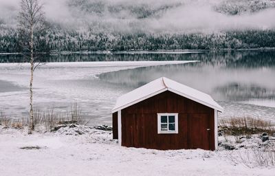 Traditional red cabin overlooking a snow covered lake and forest